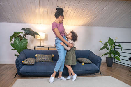Mom with little daughter standing hugging in cozy room