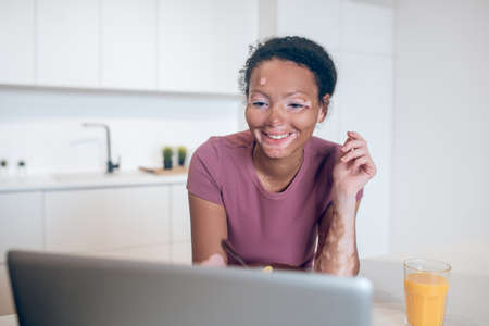 Young mulatta watching something on internet and smiling