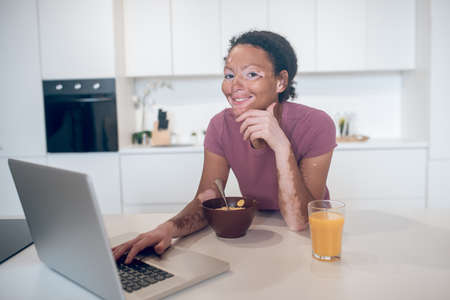 Young mulatta watching something on internet and smiling
