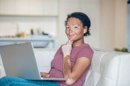 Cute young woman working on a laptop and looking thoughtfulの写真素材
