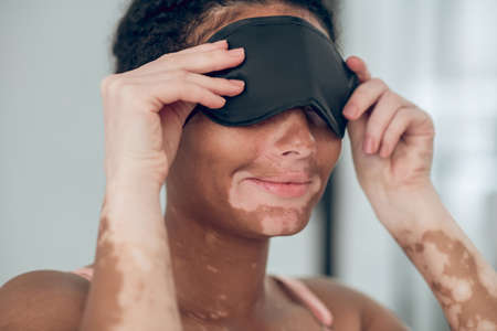 Young mulatta putting on a mask for sleepの写真素材