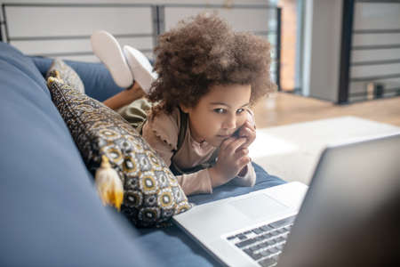 Interested little african american girl looking at laptop