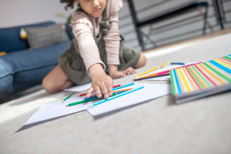 Little girls hand reaching for pencil