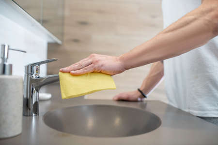 A man in a white tshirt doing some housework and cleaning