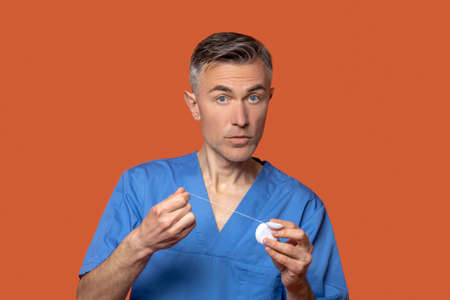 Man in medical clothes with dental floss in hands