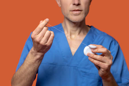 Man in medical suit showing dental floss
