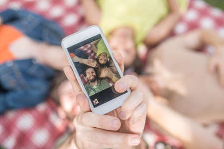 Hand showing photo of young people on smartphoneの写真素材