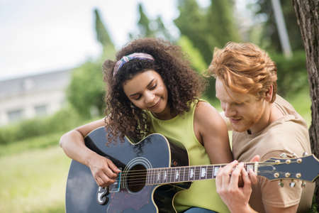 Guy teaching his girlfriend to play guitarの写真素材