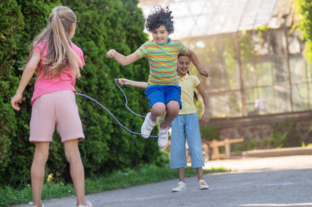 Boy in jump and two girls with skippingropeの写真素材