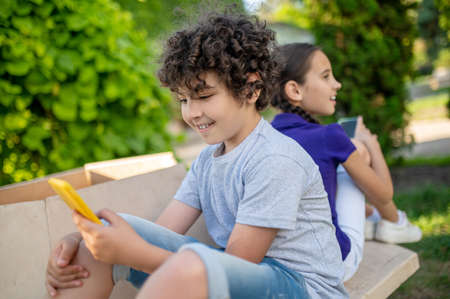 Children with smartphones in green parkの写真素材