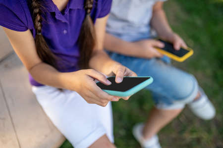 Children with smartphones outdoors in summer