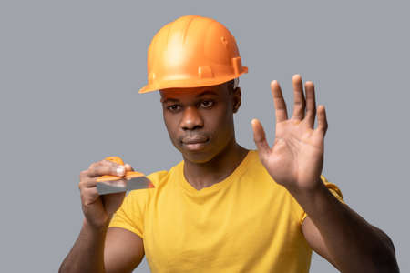 A dark-skinned construction engineer in a protective hemlet holding a floatの写真素材