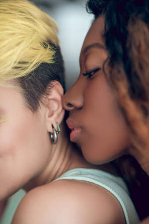 Dark-skinned woman mouth approaching her girlfriend earの写真素材