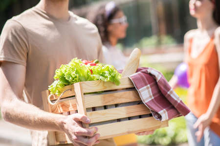 Box with vegetables and bread in hands of guyの写真素材