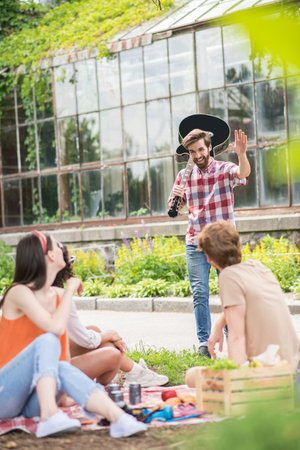 Guy with guitar meeting friends in parkの写真素材