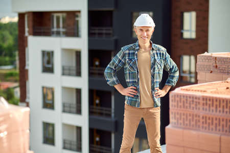 Joyous attractive worker in a hardhat atop a half-constructed buildingの写真素材