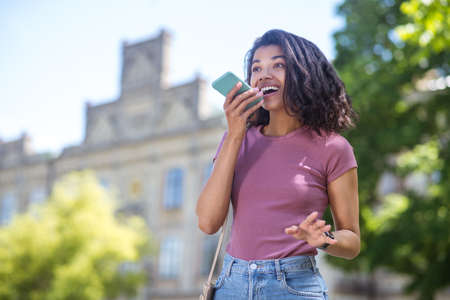 Pretty smiling mulatta with a smartphone looking enjoyed and happy
