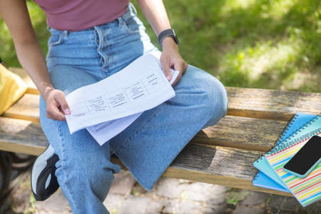 A girl in a pink tshirt holding sitting on the bench in the park
