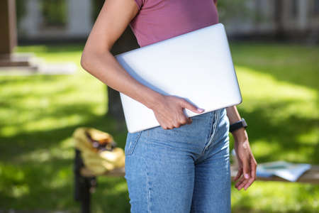 A girl in a pink tshirt with a laptop in the parkの写真素材