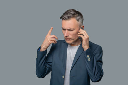 Serious gesturing man talking on smartphone