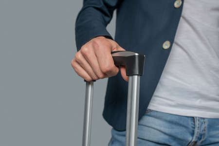Mans hand holding telescopic handle of suitcaseの写真素材