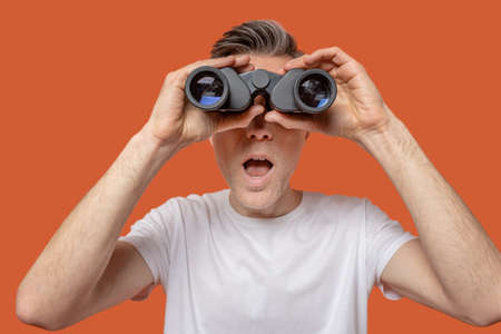 Man looking through binoculars with open mouthの写真素材