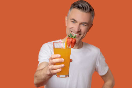 Successful man holding out glass of fresh juiceの写真素材