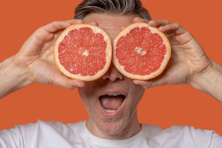 Close-up of mans face and halves of graperuitの写真素材