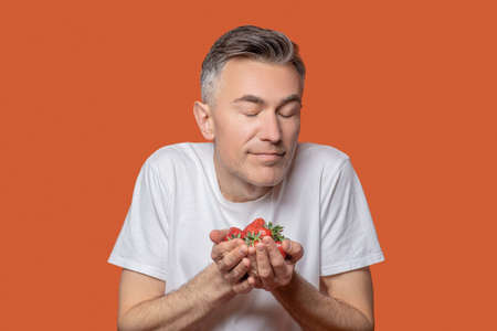 Man with closed eyes holding handful of berriesの写真素材