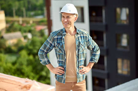 Happy worker on the top floor of a built structure looking away