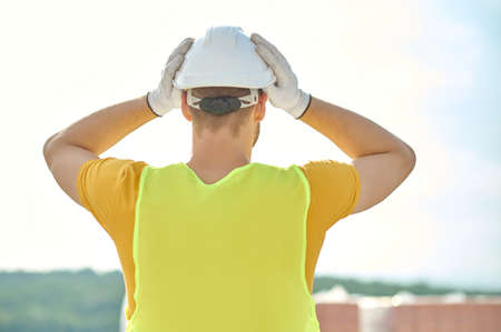 Builder covering his head with a protective helmet before work