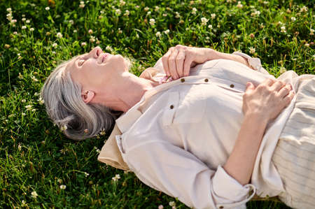 Woman lying dozing on green lawnの写真素材