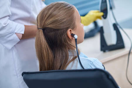 Back view of girl inearphone in otolaryngologists office