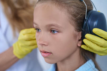 Close-up of girl and doctors hands putting on headphonesの写真素材