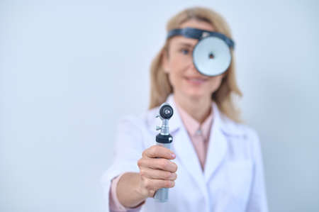 Woman in white coat with mirror and otoscopeの写真素材