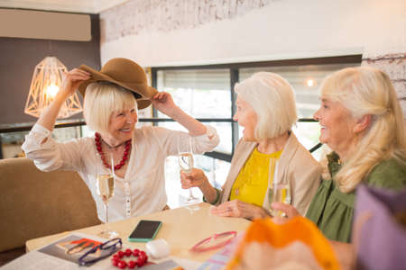 Women sitting looking excited while trying on a new hatの写真素材