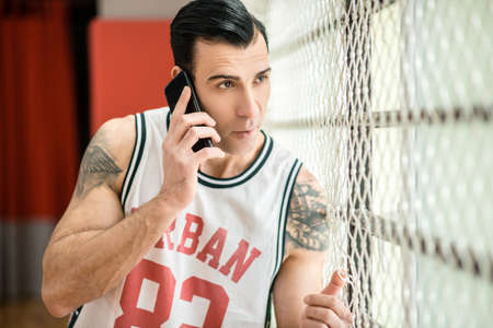 Young sportsman with tatoo talking on the phone