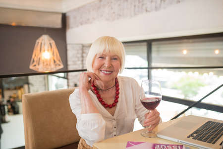 Elegant senior woman having some wine and smilingの写真素材