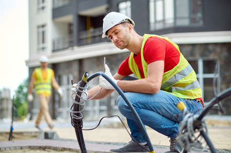 Concentrated skilled construction worker in cotton gloves installing electricityの写真素材