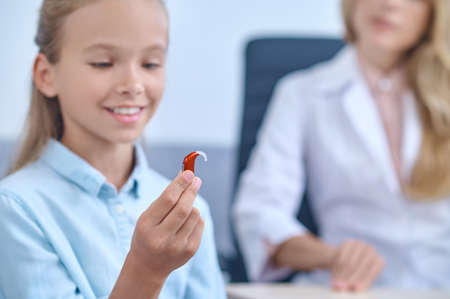 Joyful school-age girl with listening apparatus in hand