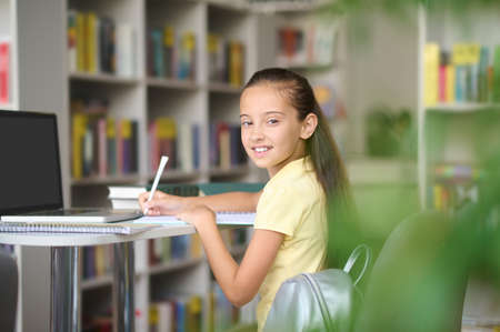 Cheerful pupil writing down in her notebookの写真素材