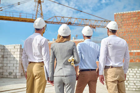 Four people examining in safety helmets a new construction object