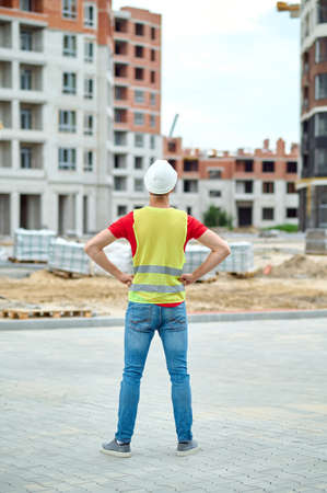 Experienced builder in a safety helmet examining a building area