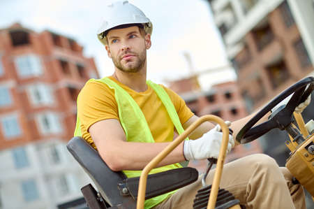 Focused man in a construction vehicle looking into the distance