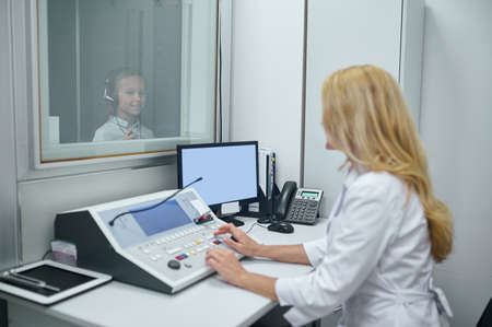 Girl in headsets standing in the soundproof boothの写真素材