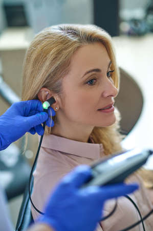Calm attractive blonde middle-aged woman having her hearing checked