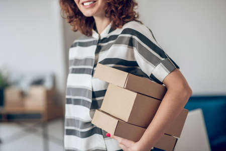 Smiling joyous female worker with packages standing insidの写真素材