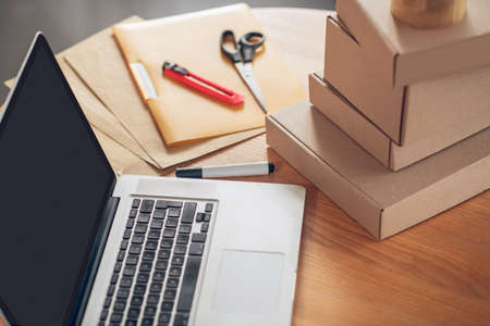 Laptop and product packages stacked on the deskの写真素材