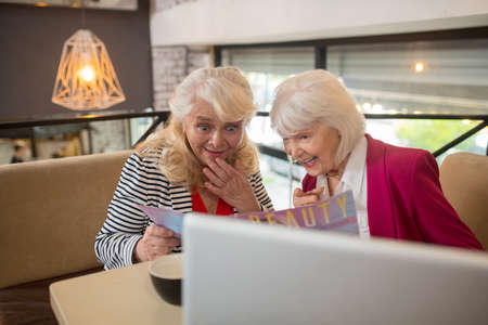 Good-looking aged ladies sitting at the laptop and looking interested