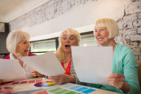 Three well-dressed aged ladies discussing a new collection of dressesの写真素材